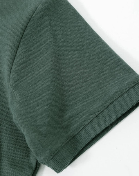 A close-up of a dark green cotton stretch polo shirt sleeve, featuring a smooth fabric texture and a logo.