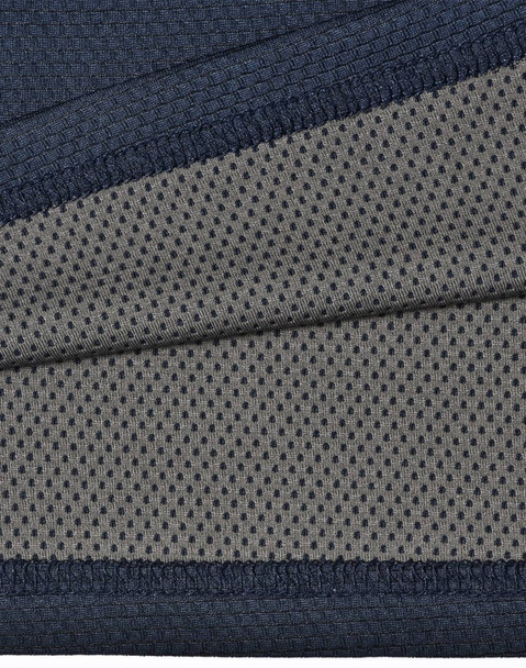 A close-up of a two-tone polo shirt featuring a navy blue top section and a grey, dotted underlay. The fabric is textured and breathable.