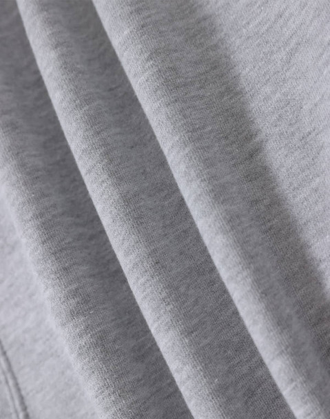 A close-up of soft grey fabric, highlighting multiple folds and textures of a fleecy hoodie.