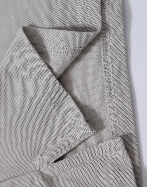 A close-up of a light grey polo shirt, showing the textured fabric and stitching details. The shirt features a logo.