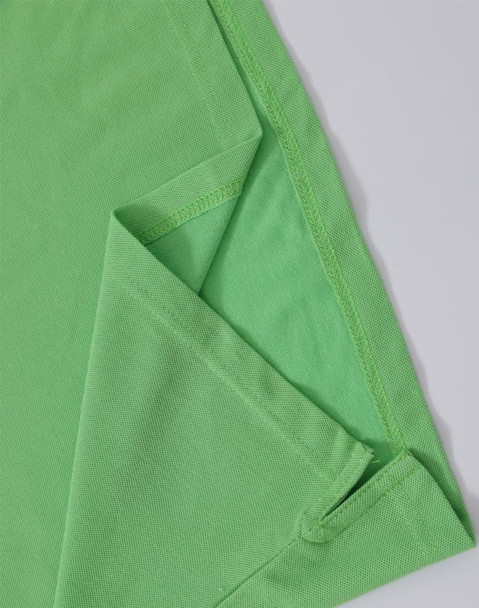 A green ladies' polo shirt featuring a folded sleeve and a hem detail, with a small logo present.