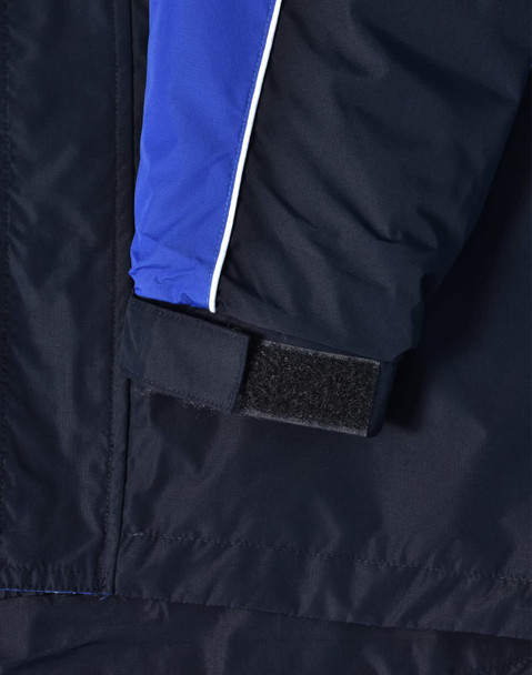 A close-up of a navy jacket featuring blue and white detailing, with a Velcro cuff closure. It has a logo on it.