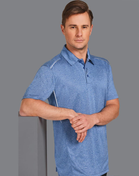 A blue short sleeve polo shirt with a subtle texture and a logo. The model stands casually with arms crossed.