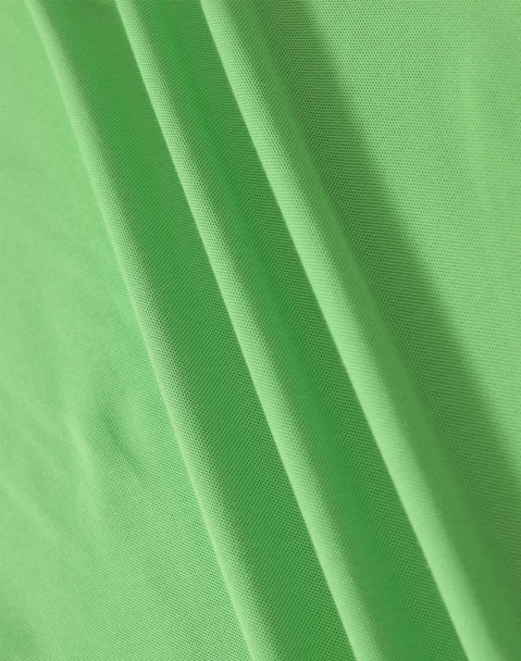 A close-up of soft, textured fabric in vibrant green, showcasing the material of a polo shirt.