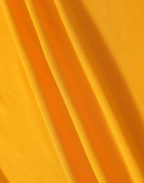 A close-up of yellow fabric featuring a textured weave, showcasing its smooth and soft surface.