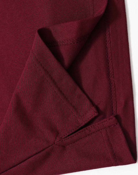 A close-up of the hem and fabric of a burgundy polo shirt, featuring a logo on one side.