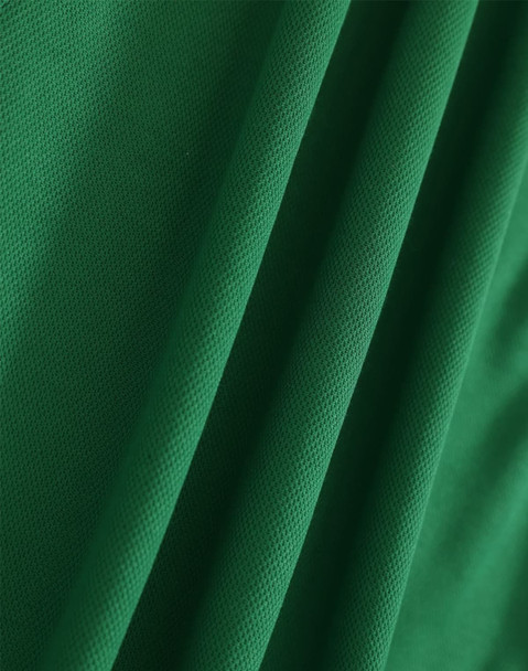 A close-up of textured green fabric, showcasing the weave and draping of the material.