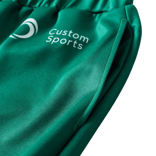 A close-up of unisex adult sports shorts in green, featuring a logo and a smooth polyester fabric.