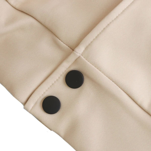 A close-up of a beige varsity jacket featuring two black buttons on the sleeve.
