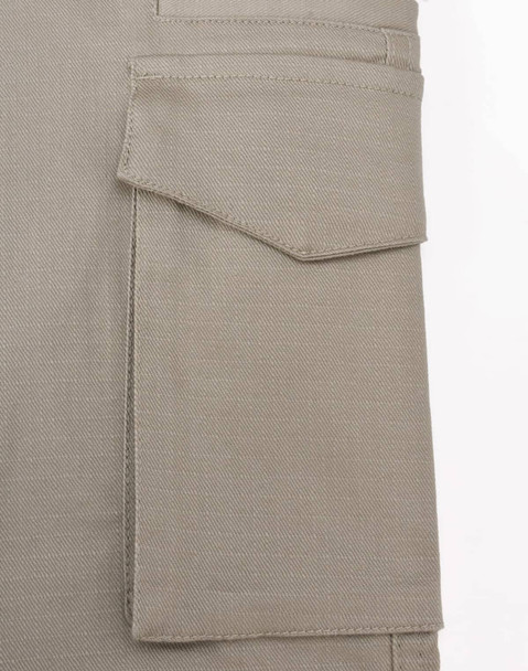 A close-up of a beige work pant pocket featuring a flap, showcasing the fabric texture and stitching detail.
