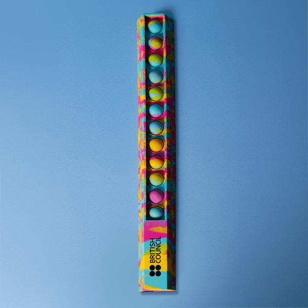 A 30cm popper ruler featuring a vibrant design with blue and multicoloured dots, alongside a logo.