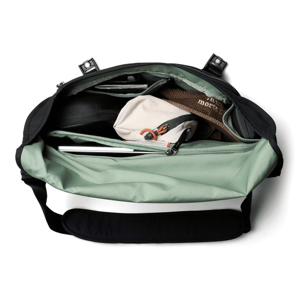 A black and mint green messenger bag opened to reveal multiple compartments, including a laptop sleeve and pouches.
