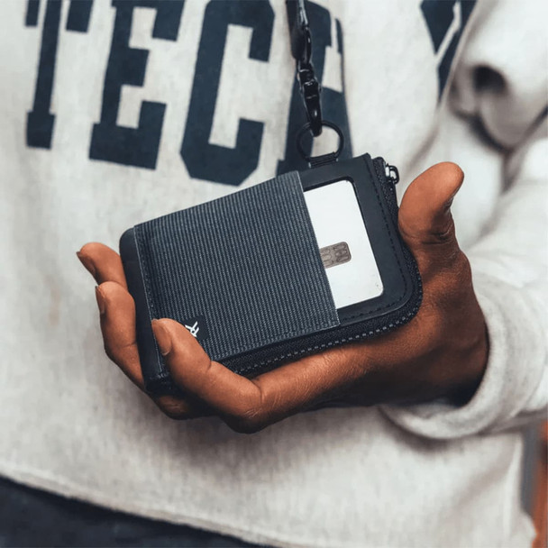 A hand holding a black and grey Thread Zipper Wallet, featuring a zippered compartment and a card slot.