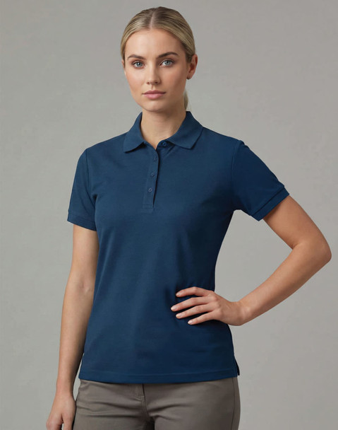 A navy blue ladies ultrafine cotton pique polo with a collar and short sleeves. The model is posing with hands on her hips.