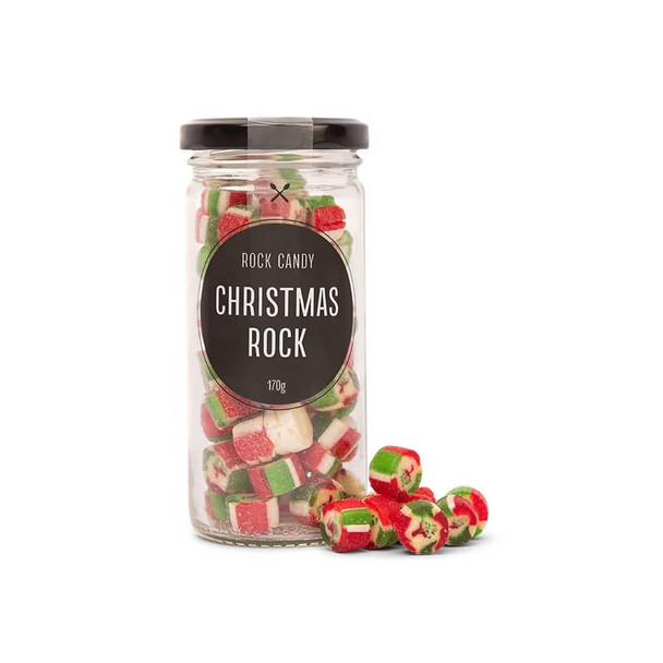 A glass jar filled with red, green, and white rock candy pieces, with some scattered outside. The jar has a black lid.