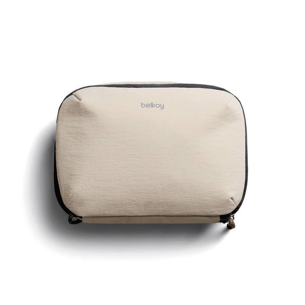A beige tech kit with a zip closure and a logo on the front, featuring a textured fabric design.