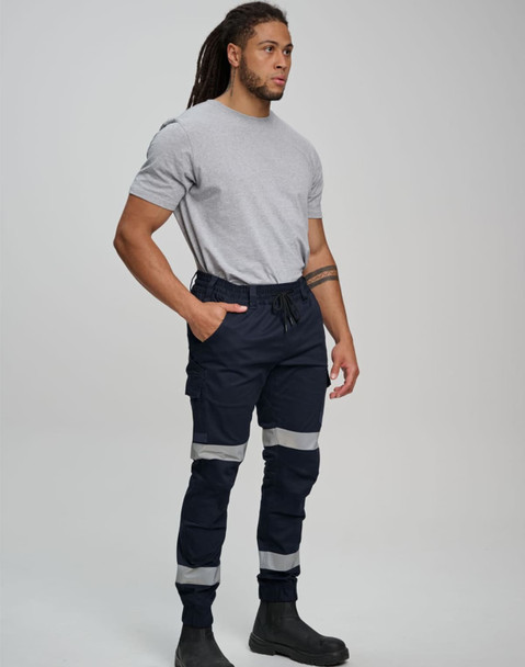 A man wearing navy cotton stretch drill cuffed work pants with reflective tape, paired with a grey t-shirt and black boots.