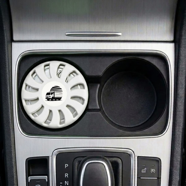 A white air freshener sits in a car cup holder, featuring a circular design and a logo.