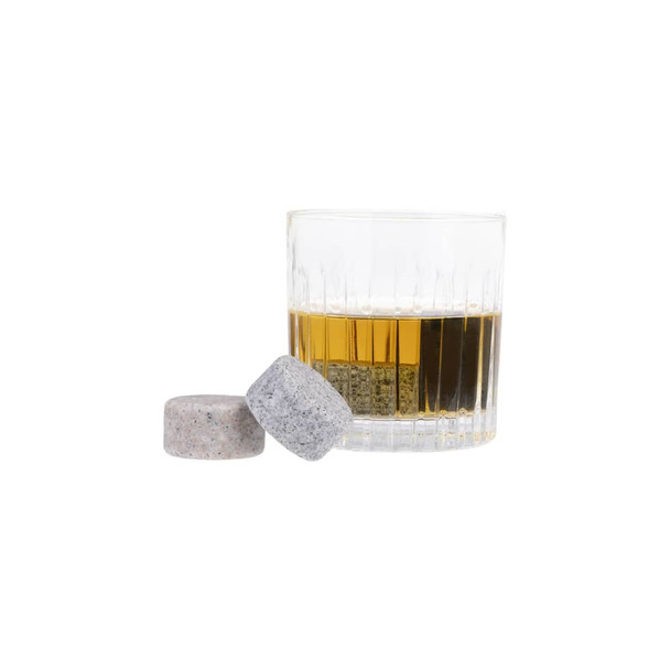 A glass of whisky with two whisky discs, one grey and one light grey, beside it.
