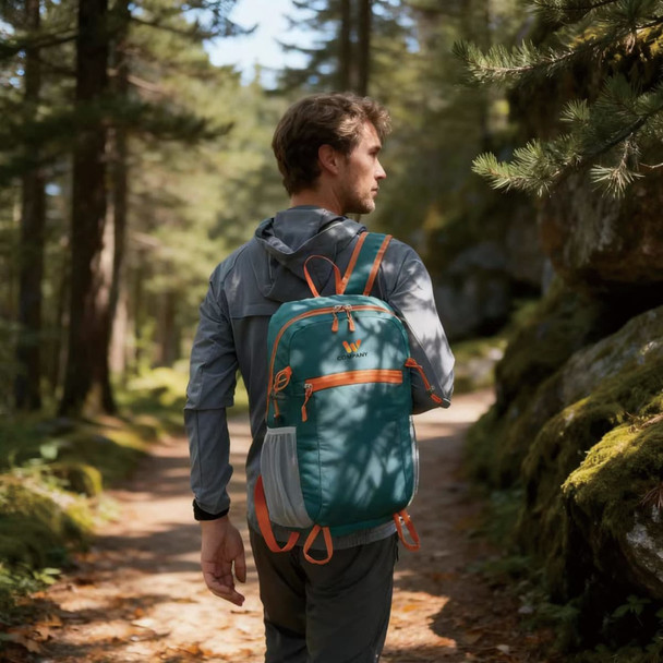 A packable hiking backpack in teal and orange, carried by a person on a forest trail.