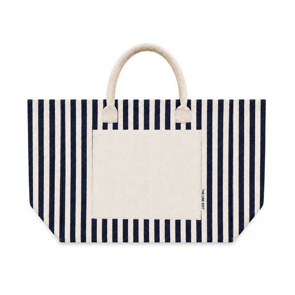 A striped tote bag featuring navy blue and cream colours with two handles and a front pocket. It has a logo.