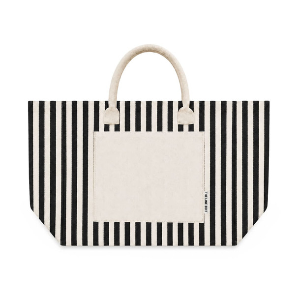 A striped tote bag featuring black and cream colours, with a solid cream pocket and handles. It has a brand logo.