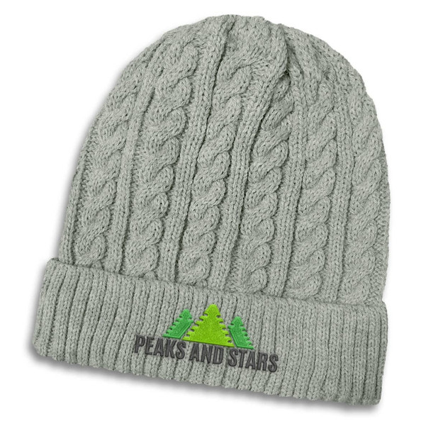 A grey knit beanie with a cable pattern and a logo featuring trees on the front.