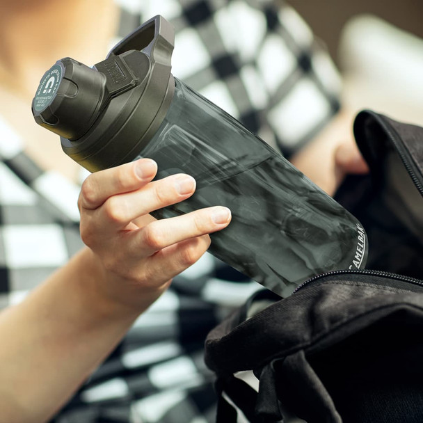 A drink bottle with a black lid and a transparent body being taken from a black bag. Features a logo.