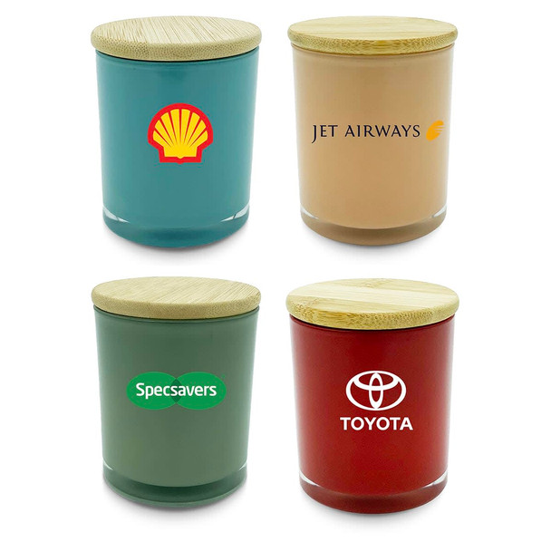 Four medium candles in various colours: teal, peach, green, and red, each with a bamboo lid and a logo.