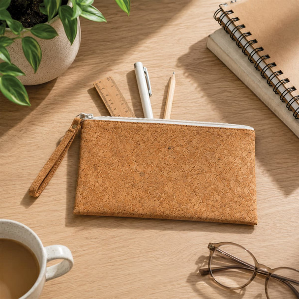A cork pencil case with a zippered closure, surrounded by pens, a ruler, a notepad, and a cup of coffee.