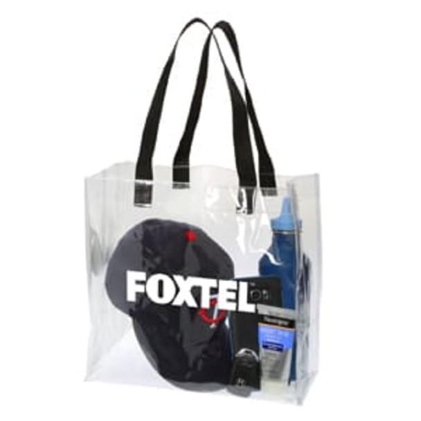 A clear tote bag with black handles containing a hat, bottle, sunscreen, and other items, featuring a logo.