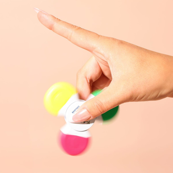 A hand spins a multi-coloured highlighter with pink, yellow, green, and orange caps against a peach background.