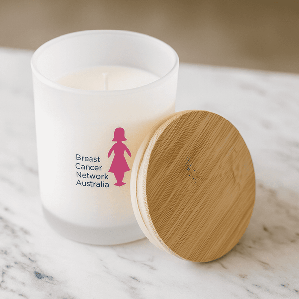 A medium white candle with a bamboo lid and a logo on the frosted glass, set on a marble surface.
