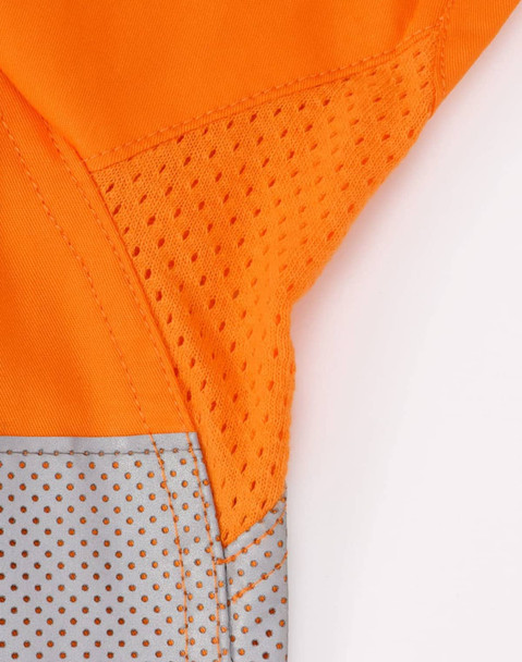 An orange long-sleeve shirt featuring perforated silver tape detailing. The shirt has a logo.