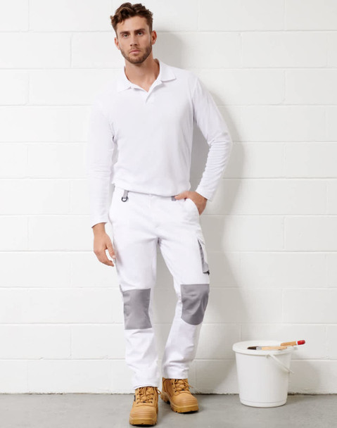 White unisex cargo work pants with grey accents, paired with a long-sleeve white top and work boots, standing next to a paint bucket.