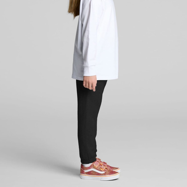 A child wearing black track pants with a white long-sleeve top and pink patterned shoes, standing sideways. A child wearing black track pants with a white long-sleeve top and pink patterned shoes, standing sideways.