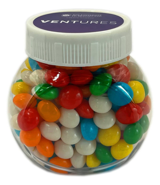 A plastic jar filled with chewy fruit candies in red, green, yellow, blue, and white colours.