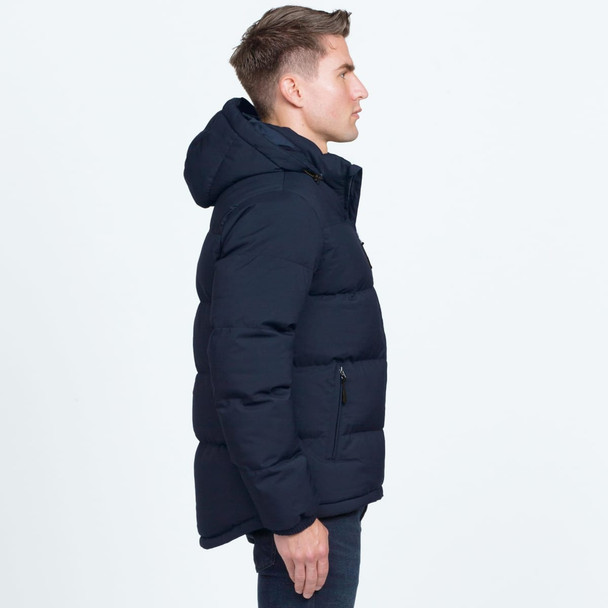 A side view of a navy blue puffer jacket featuring a hood and a logo. The jacket has a padded design. A side view of a navy blue puffer jacket featuring a hood and a logo. The jacket has a padded design.