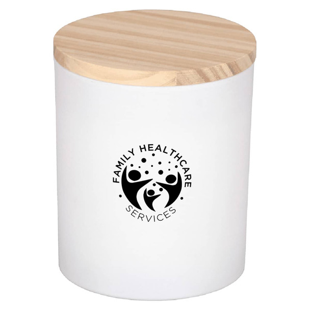 A white candle jar with a wooden lid and a logo on the front, featuring a simple design.