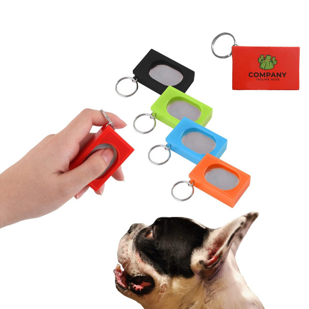 A set of four pet training clickers in red, black, green, and orange, held by a hand, with a dog in the foreground.