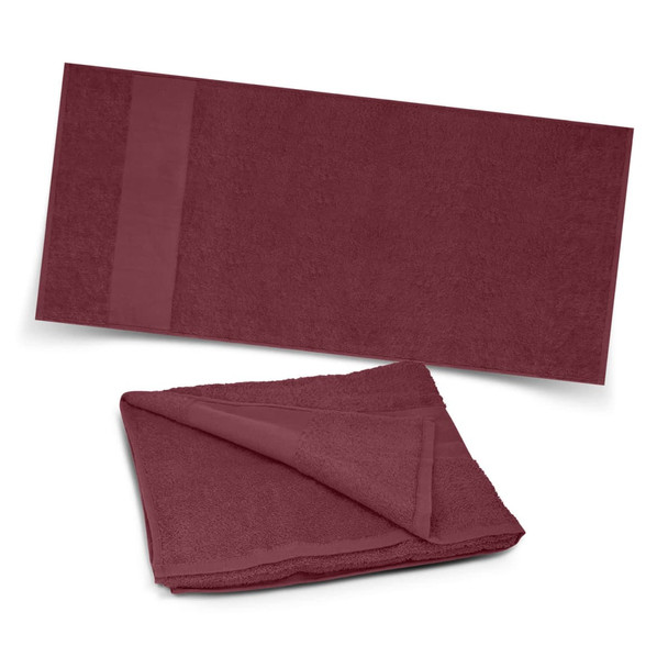 A maroon beach towel with a textured surface and a folded section, featuring a subtle logo.