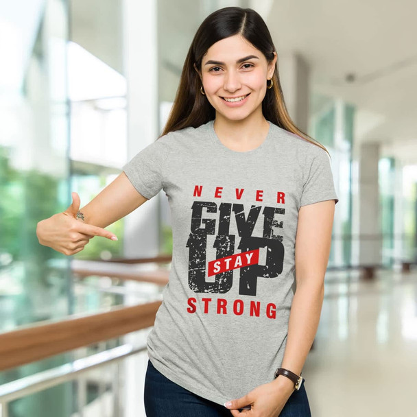 A woman wearing a grey TRENDSWEAR original women's T-shirt with a motivational print, pointing and smiling. A woman wearing a grey TRENDSWEAR original women's T-shirt with a motivational print, pointing and smiling.