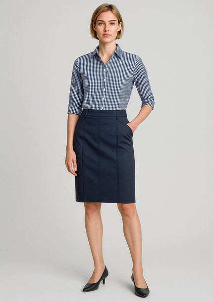 A woman wears a navy mid-waist stretch chino skirt paired with a checked shirt and heels. The outfit includes a logo.