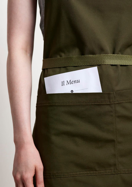 A green apron featuring a front pocket holding a menu card, with a simple logo.
