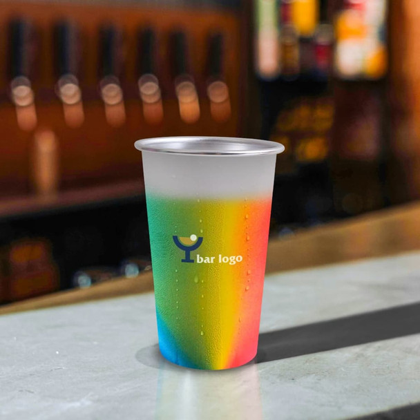 A colour changing cup featuring a gradient of rainbow hues, set on a bar countertop with a logo visible.