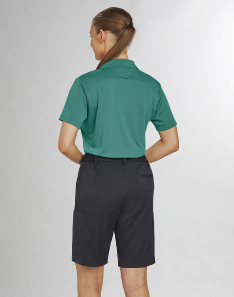 A woman in a green polo shirt and black utility cargo shorts, viewed from the back. The shorts have pockets and are knee-length.