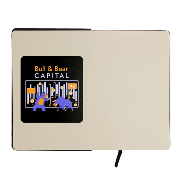 An A5 notebook with a black cover and an illustration featuring a bull and bear on the inner page, includes a logo.