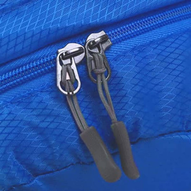 A blue compressed bag featuring dual zippers with black pulls and a textured surface. The bag has a small logo.