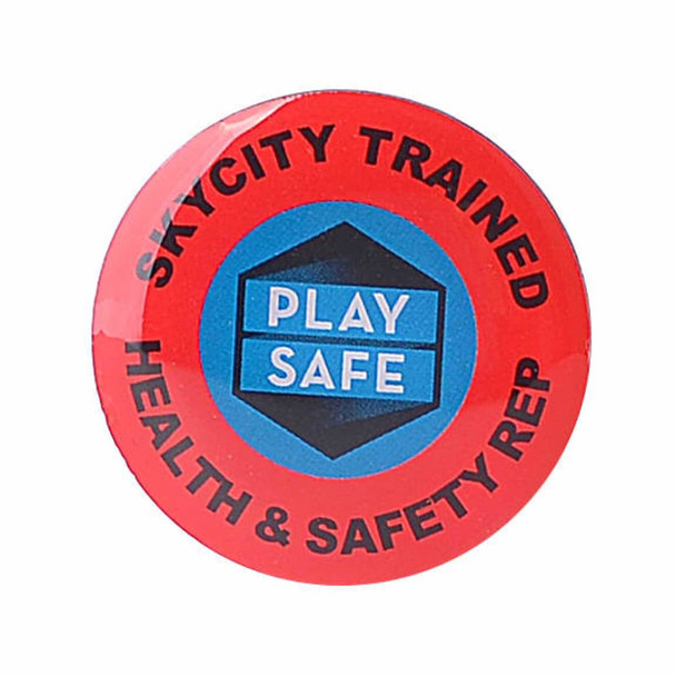 A red lapel pin featuring a circular design with a logo and text in blue and black.