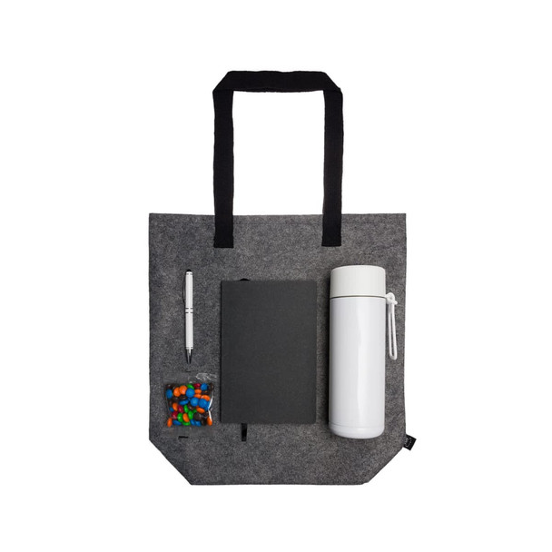 A gray tote bag containing a drink bottle, a notebook, a pen, and a small bag of candies.